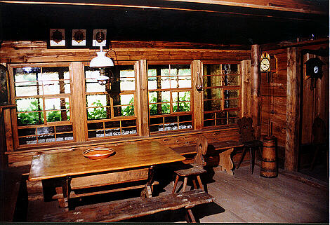 Die Stube; im Hintergrund der Umgang (Schild), der die Innenräume von der Außenseite des Hauses trennt.