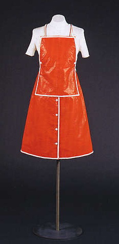 Tagesmini Orangefarbener Latzrock aus Lacklederimitat mit "Schürzenträgern", weißer Rippenpulli aus Baumwolle André Courrèges, Paris 1973 Foto: SMB-SPK, Saturia Linke